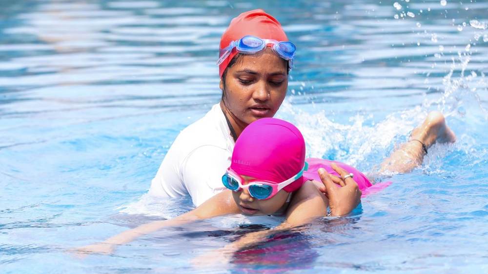 A swim instructor in the water guiding a young girl through a one-on-one lesson